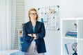 Smiling middle aged businesswoman near grid mood board with pinned work-life balance wheel diagram on her work space