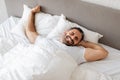 man stretching his arms wakes up on cozy bed indoor