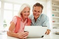 Smiling Middle Aged Couple Looking At Digital Tablet