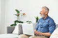 Modern middle-aged bearded man using laptop computer sitting on the couch at home Royalty Free Stock Photo