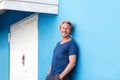 Smiling middle aged man leaning against blue wall Royalty Free Stock Photo