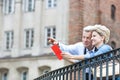 Smiling middle-aged man showing something to woman with guidebook in city