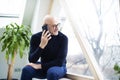 Smiling middle aged man talking using his mobile phone while sitting at the window Royalty Free Stock Photo