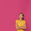 Smiling middle aged pretty european blonde female in yellow t-shirt looking up at empty space