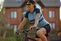 Smiling middle aged woman in cap with glasses cycling in summer park, cycling cardio training, city walks with bike Royalty Free Stock Photo