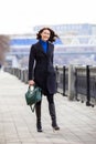 Smiling middle-aged woman in a dark coat goes on embankment