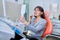 Smiling middle aged woman in dental chair with mirror looking at her teeth Royalty Free Stock Photo