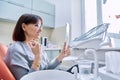 Smiling middle aged woman in dental chair with mirror looking at her teeth Royalty Free Stock Photo