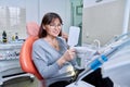 Smiling middle aged woman in dental chair with mirror looking at her teeth Royalty Free Stock Photo