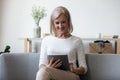 Smiling middle aged woman using computer digital tablet. Royalty Free Stock Photo