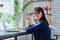 Middle-aged woman at coffee shop drinking coffee, with laptop, looking at camera Royalty Free Stock Photo