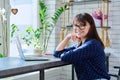 Middle-aged woman at coffee shop drinking coffee, with laptop, looking at camera Royalty Free Stock Photo