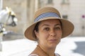 A smiling middle-aged woman in a straw hat against the background of a European city, a horse-drawn carriage. Royalty Free Stock Photo