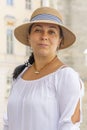 A smiling middle-aged woman in a straw hat against the background of a European city, a horse-drawn carriage. Royalty Free Stock Photo