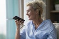Smiling middle aged woman talk on loudspeaker on smartphone Royalty Free Stock Photo