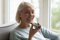 Smiling middle-aged woman use voice assistant on smartphone Royalty Free Stock Photo