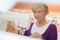 Smiling middle aged woman using sewing machine in laundry Royalty Free Stock Photo