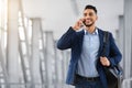 Smiling Middle Eastern Man Talking On Mobile Phone While Walking At Airport Royalty Free Stock Photo