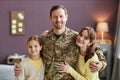 Smiling military man embracing wife and daughter