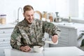 Smiling military man pouring milk in bowl