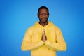 Smiling millennial african american guy prayer in hoodie with eyes closed making pray sign Royalty Free Stock Photo