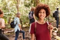 Smiling millennial African American woman hiking in a forest with friends, waist up, close up