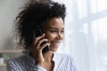 Smiling African American woman look in window talking on smartphone Royalty Free Stock Photo