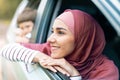 Smiling millennial arab female in hijab and boy look out the open window and enjoy journey in car Royalty Free Stock Photo