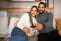 Smiling millennial arabic guy with beard and remote control hugs european lady, watch TV, eat popcorn Royalty Free Stock Photo