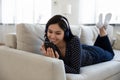 Smiling Asian girl in headphones using smartphone at home Royalty Free Stock Photo