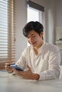 Smiling millennial Asian man using mobile banking application to pay online bills Royalty Free Stock Photo