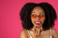 Smiling millennial black woman student in glasses eating strawberry, look at empty space