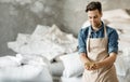 Smiling millennial brewery owner or worker in apron holds wheat or barley grains in hands in warehouse Royalty Free Stock Photo