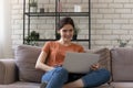 Happy young woman sit on couch working on laptop Royalty Free Stock Photo