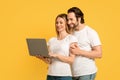 Smiling millennial caucasian man hugging woman in white t-shirt and look at laptop making video call Royalty Free Stock Photo