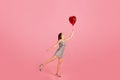 Smiling millennial caucasian woman in dress hold red heart balloon