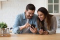 Happy couple have fun at home using cellphones in kitchen Royalty Free Stock Photo