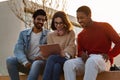 Smiling millennial diverse modern students look at tablet, have video call, online lesson, study together at university