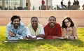 Smiling millennial diverse modern students study together, rest from lesson, lie on grass in university