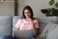 Smiling ethnic woman rest on couch using laptop Royalty Free Stock Photo