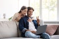 Smiling millennial european couple communicate with family remotely, wave hand, showing peace sign Royalty Free Stock Photo