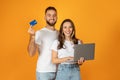 Smiling millennial european couple shopaholics use computer, show credit card
