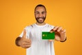 Smiling millennial european man in white t-shirt show credit card, recommend finance Royalty Free Stock Photo