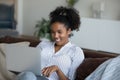 Smiling millennial african woman using computer at home.