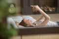 Happy woman relaxing on cozy couch using cellphone Royalty Free Stock Photo