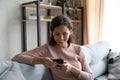 Smiling millennial girl relax on sofa using cellphone Royalty Free Stock Photo