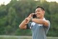 Smiling millennial man in sports clothes talking on mobile phone and checking time on watch Royalty Free Stock Photo