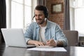 Man wear headset studying online seated at desk with laptop