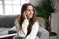 Smiling millennial mestizo woman talking on the phone at home