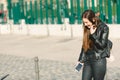 Smiling millennial woman, happy girl holds cellphone while walking down the street Royalty Free Stock Photo